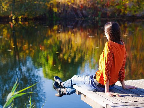 The Importance of Mindfulness in Addiction Recovery - woman sitting on lake
